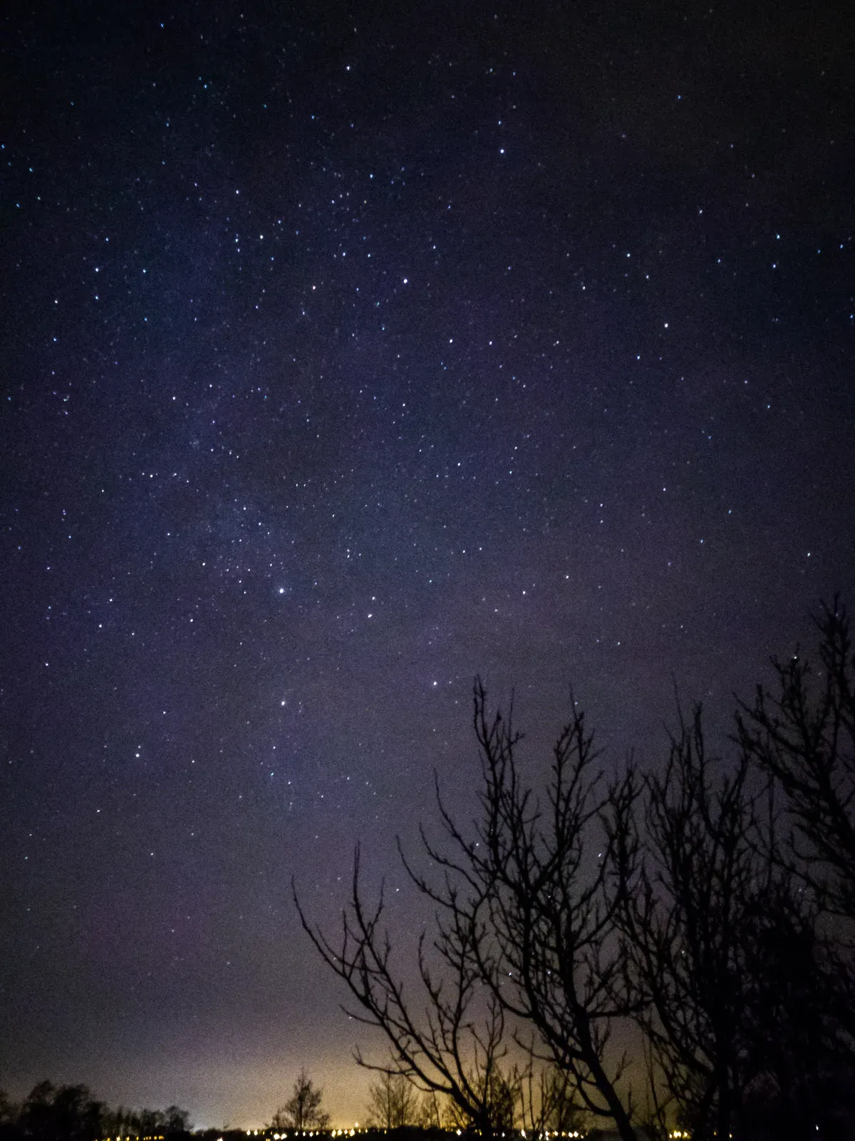 The night sky photographed from the edge of the city, near a lake.