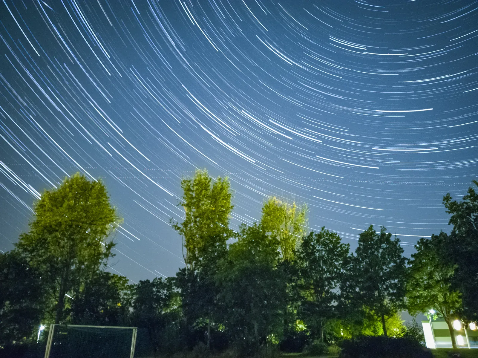 Concentric star trails over a dark landscape, composed from 360 exposures.
